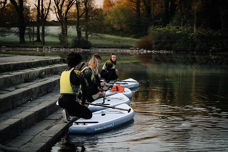 four adults getting on the paddle boards at castlewellan lake