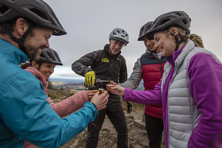 Three mountain bikers drinking tea and eating traybakes at Carrick Cottage, Mourne Mountains